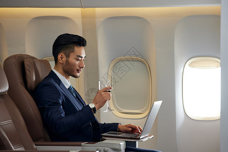 商务男士飞机商务舱喝红酒办公图片