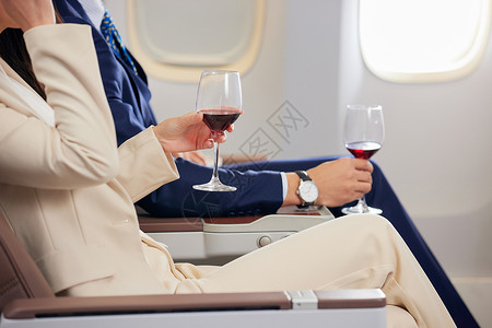 商务男女飞机头等舱里品尝红酒特写高清图片
