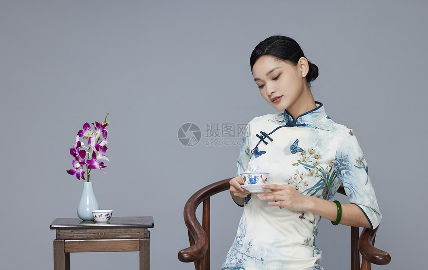 年轻旗袍女性端坐品茶图片