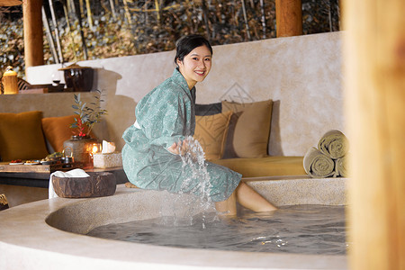 穿着日式浴衣的女性坐在温泉旁边玩水高清图片