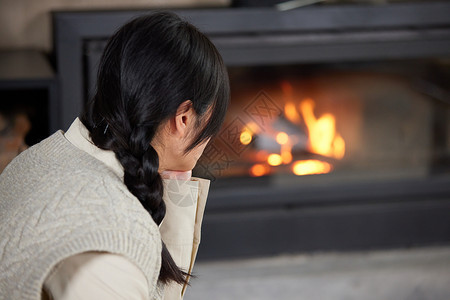 冬日夜晚坐在火炉边取暖的女性图片