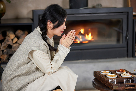 冬日夜晚坐在火炉边取暖的美女图片