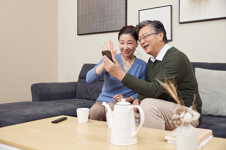 祖孙三代客厅使用手机视频聊天在家使用智能手机打视频电话的老年夫妻背景