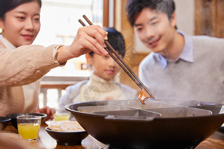 一家三口吃重庆火锅夹菜特写背景图片