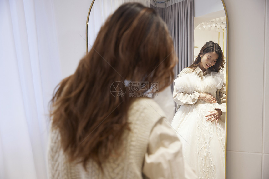 在镜子前挑选婚纱的女性图片