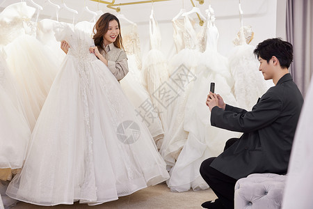 男士在婚纱店给试穿婚纱的女友拍照高清图片