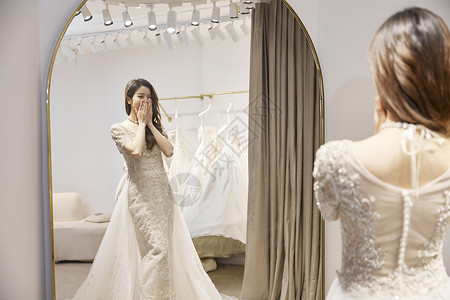 穿婚纱的女性惊喜地看镜子高清图片