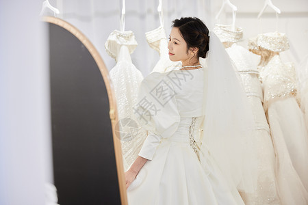穿着婚纱站在试衣镜前的新娘图片