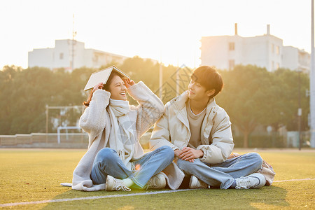 情侣学生操场看书学习的大学生情侣背景