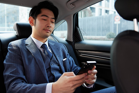 商务男性乘客坐在车里看手机背景