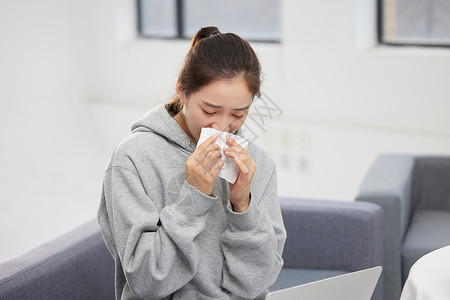 雾霾空气室内过敏的女性使用纸巾擦鼻子背景