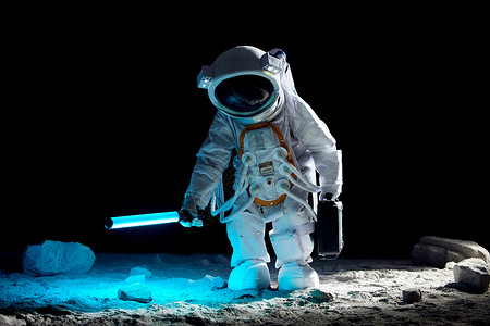 搜尋宇航员手持探照设备站在月球表面上背景