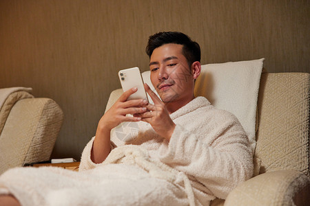 青年男性躺沙发上玩手机图片