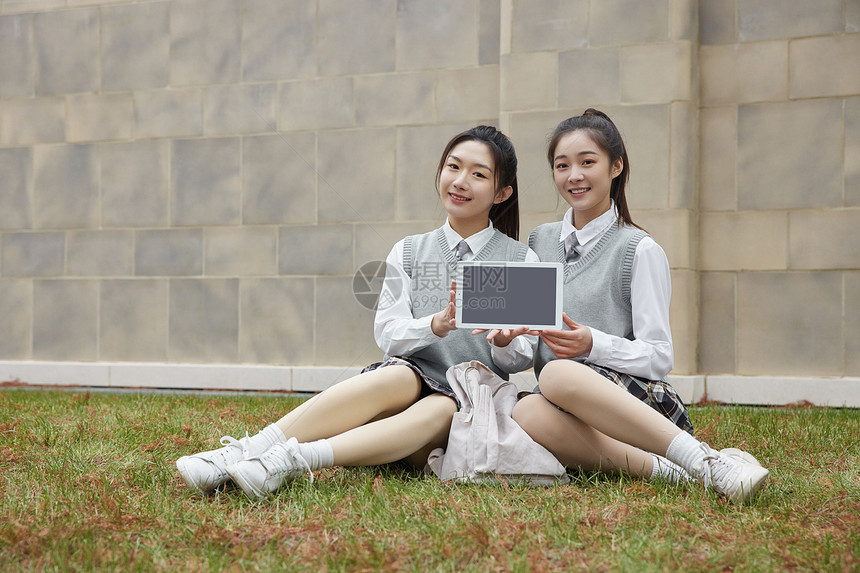 美女大学同学坐在草地上展示平板电脑图片
