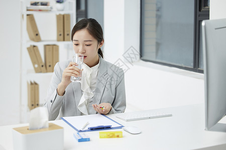生病的职场女性在办公室吃药图片素材