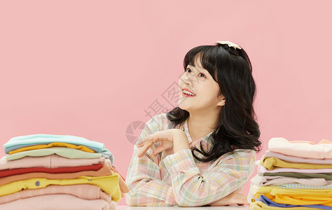 冲动消费素材甜美居家少女坐在一堆衣服边上背景