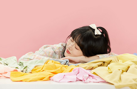 黄色衣服少女趴在一堆衣服上的可爱少女背景