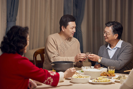民俗年味素材春节年夜饭父子喝白酒碰杯背景
