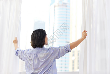 居家中年女性早晨拉开窗帘背影背景图片