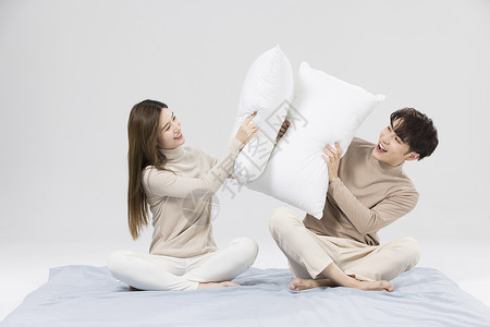 韩系情侣用枕头嬉戏打闹高清图片