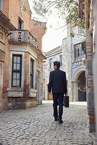 穿着中山装走在老旧街道上的男青年背景图片