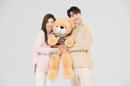 韩系情侣抱着绒毛玩偶熊背景图片
