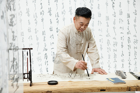 低头画水墨画的中国风中年人背景图片