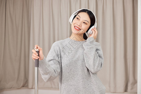 青年女性做清洁戴耳机听音乐图片