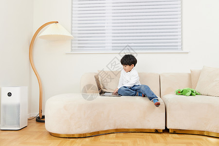 小男孩在沙发上玩耍看电脑图片