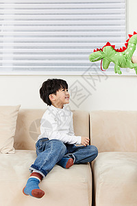 小朋友在沙发上跟玩偶玩耍高清图片