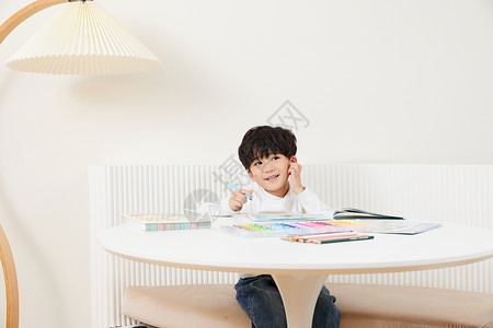 坐在桌前画画的小男孩图片