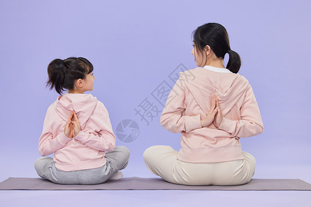 培训瑜伽母亲和女儿做瑜伽时对视背景