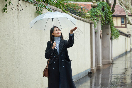 在雨中行走的女性用手接雨水背景