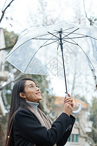 下雨天女性高举雨伞图片