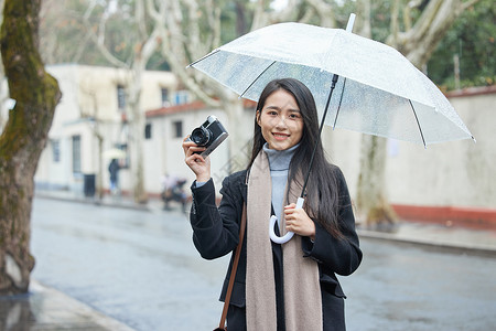 下雨天撑着伞的女摄影师高清图片