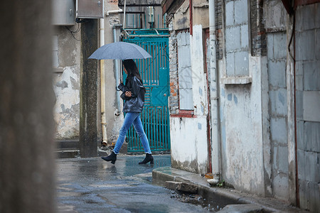 下雨天街道穿梭在老旧街道里的女性背景