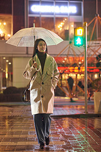 下雨夜晚过马路的都市女性背景图片