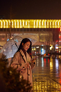 下雨天站在路边看手机的女性图片
