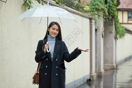 雨天撑伞的女性用手接雨水图片