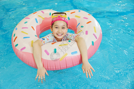 小女孩趴在游泳圈上开心戏水背景图片