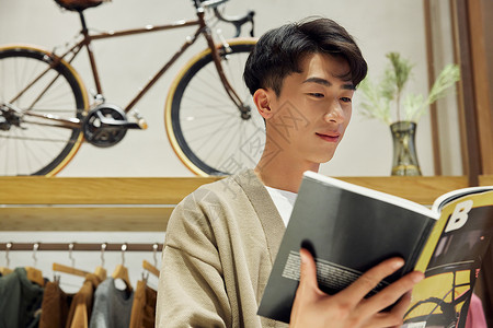 服装店阅读杂志的青年男性背景图片