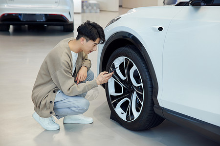 汽车4s店查看轮胎的青年男性图片