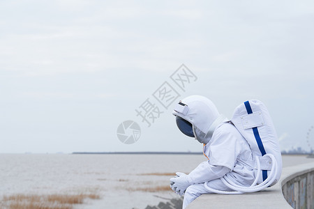 太空水宇航员户外坐在海边思考背景