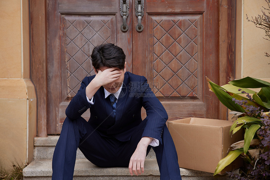 中年失业男性坐在家门口掩面丧气图片