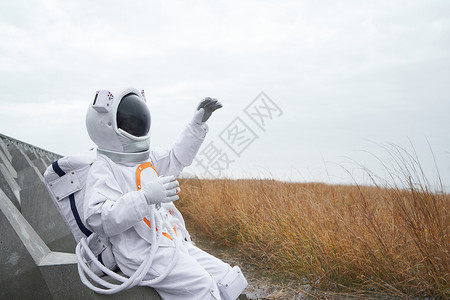 穿着宇航服的男性坐在田边背景图片