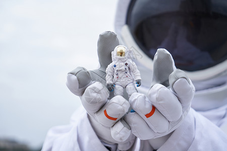 太空实验室穿着宇航服的男性拿着宇航员模型特写背景