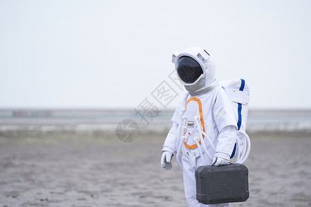 穿着宇航服的男性拿手提箱图片