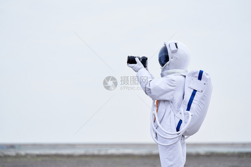 穿着宇航服的男性拿单反拍摄图片