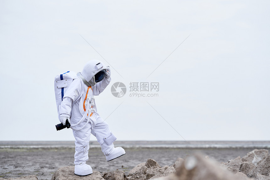 穿着宇航服的男性拿相机探索图片