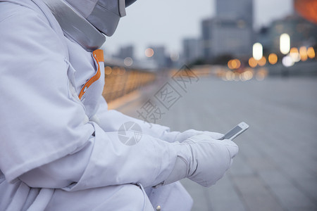 户外穿着宇航服的男性看手机特写图片